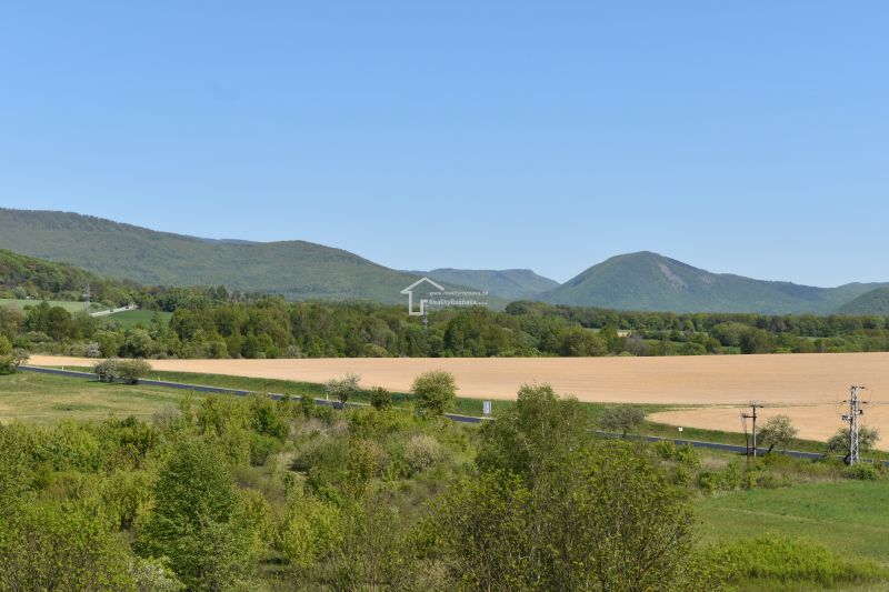 A picturesque landscape near Rožňava with fields, a road, and hills in the distance.
