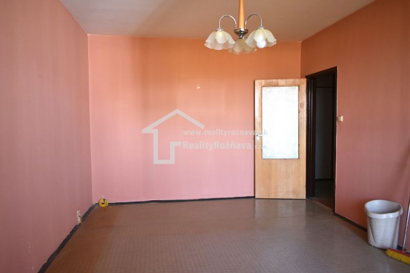 A room with pink walls and a brown floor in a 3-room apartment.