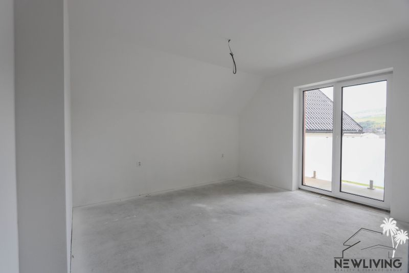 A spacious room with a gray floor and large windows in a 4-room apartment.