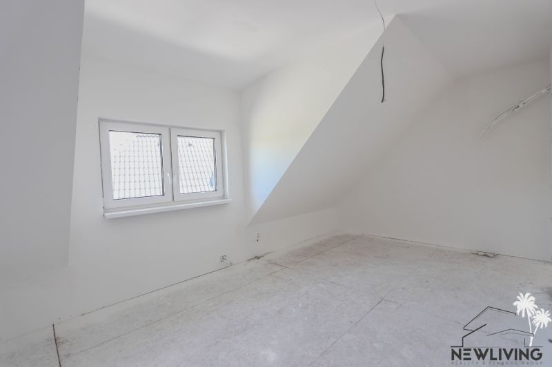 Attic room in a 4-room apartment with white walls and a skylight.