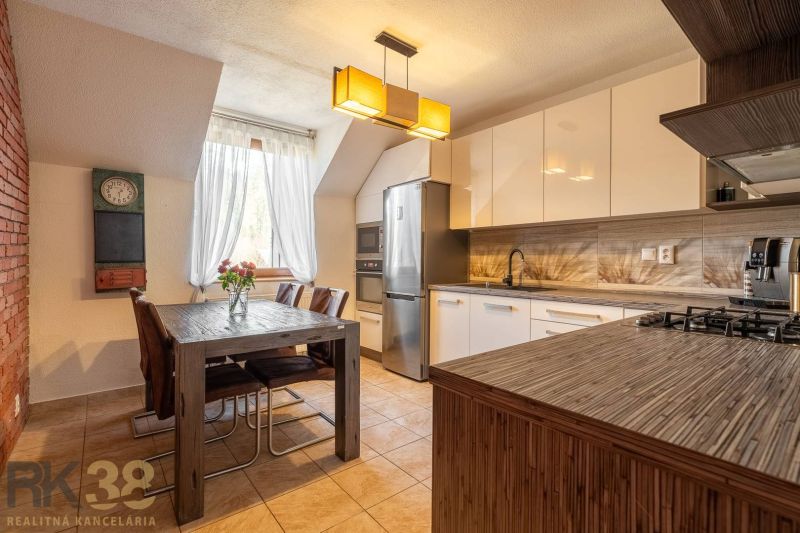 A kitchen in a 4-room apartment with a dining table, chandelier, and modern appliances.