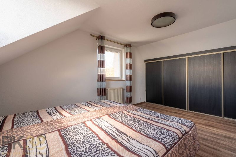 Bedroom in a 4-room apartment with a bed, a large wardrobe, and a floor with a wooden decor.