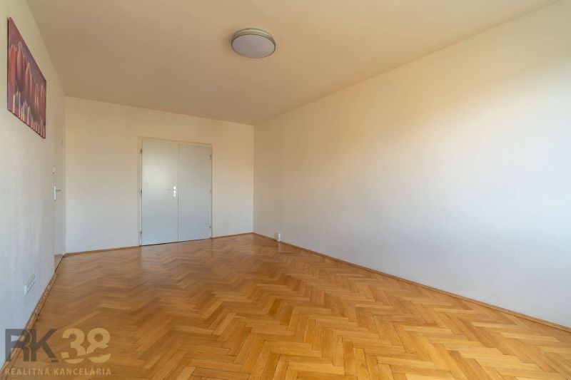 A room in a 4-room apartment with white walls and a wooden decor floor.
