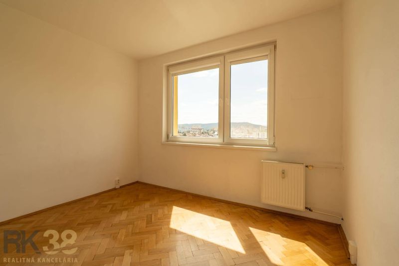 A room with a window, a radiator, and a wooden decor floor in a 4-room apartment.