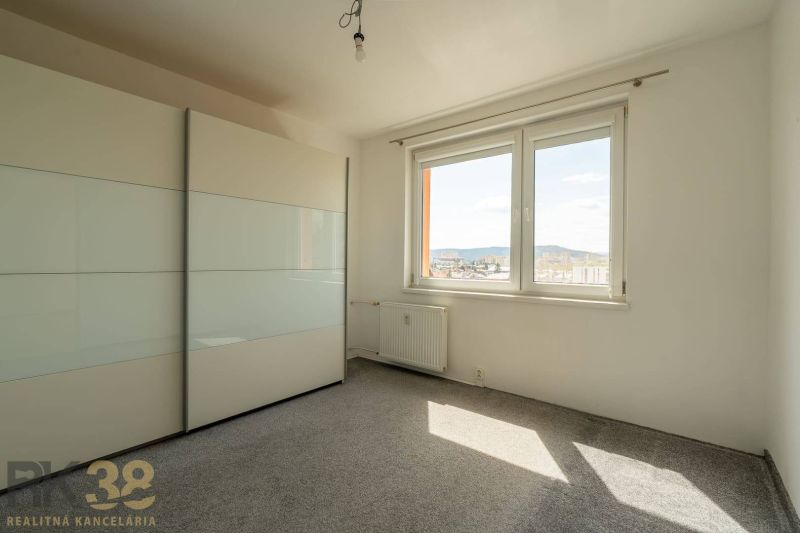 A room in a 4-room apartment with a wardrobe, carpet, and a window with a view.