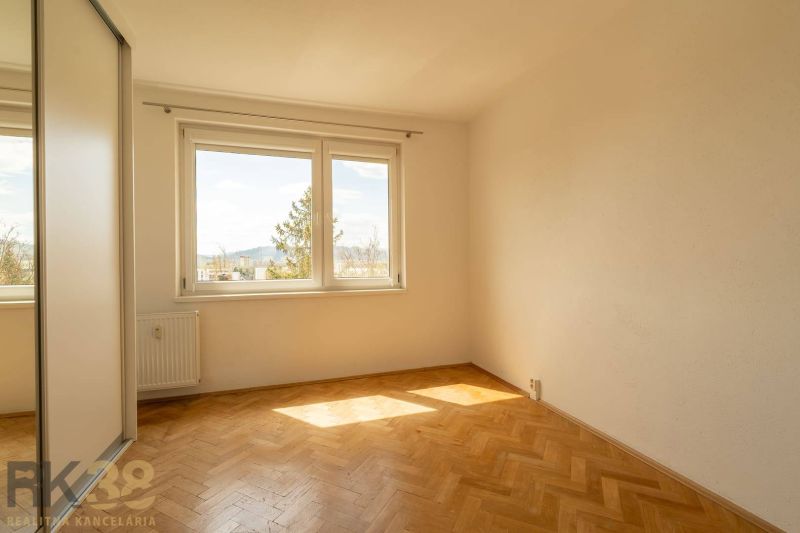 A bright room with large windows and a wooden decor floor in a 4-room apartment.