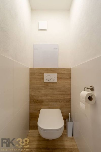 A minimalist toilet with a wall-hung WC and a floor with a wooden decor in a 4-room apartment.