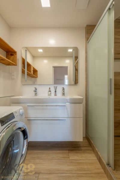 Bathroom in a 4-room apartment, sink with mirror, washing machine, floor with wooden decor.