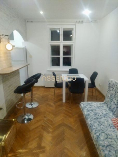 Living room in a two-room apartment with a wooden decor floor, dining table, and chairs.