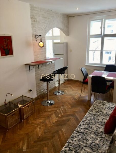 Living room with bar stools, dining table, and wood-patterned flooring.