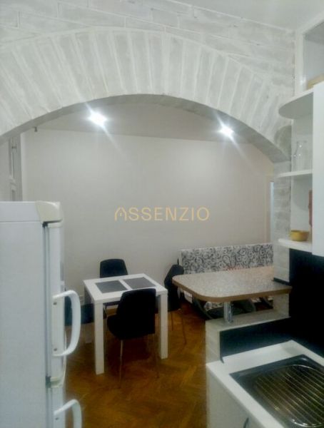 A kitchen in a 2-room apartment with an arched ceiling and a floor with a wooden decor.