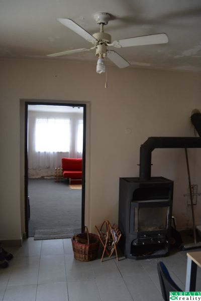 In the family house, there is a ceiling fan, a stove, and a red couch in the background.