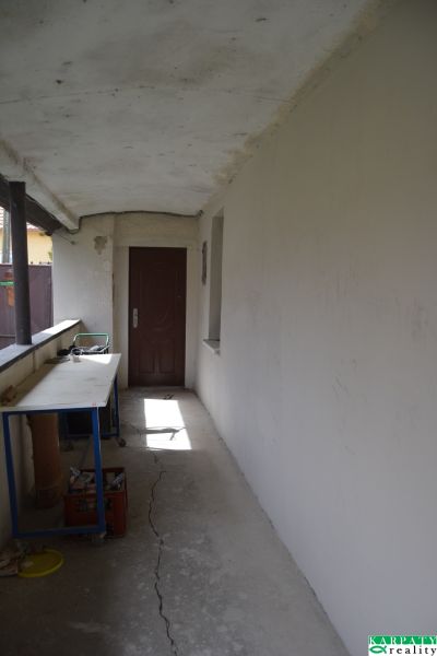 A hallway with white walls, cracks on the floor, a table, doors in a family house.