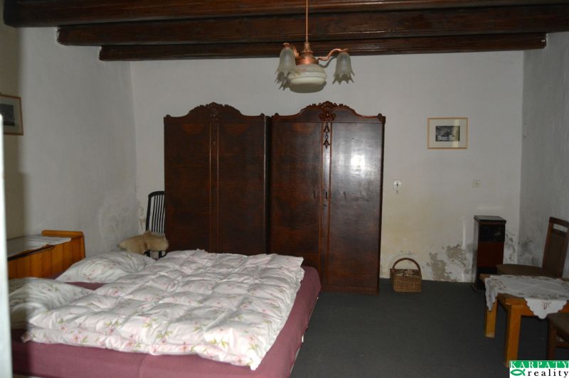 Bedroom in a family house with a bed, wardrobe, and chairs.