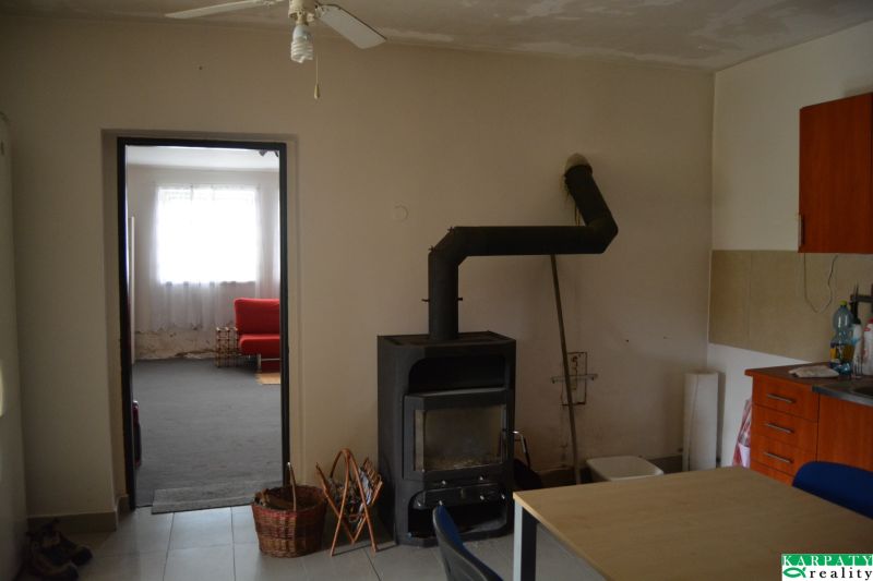 The interior of a family house with a fireplace, a fan, and a red sofa in the background.
