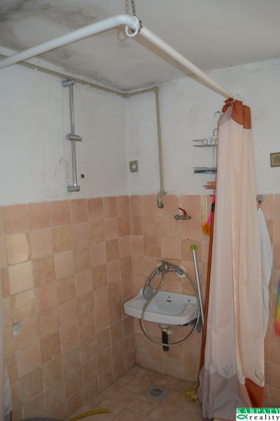 Bathroom with tiles and a curtain in a family house, simple sink.