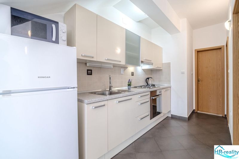 Bright kitchen in a holiday apartment with built-in appliances and tiling.