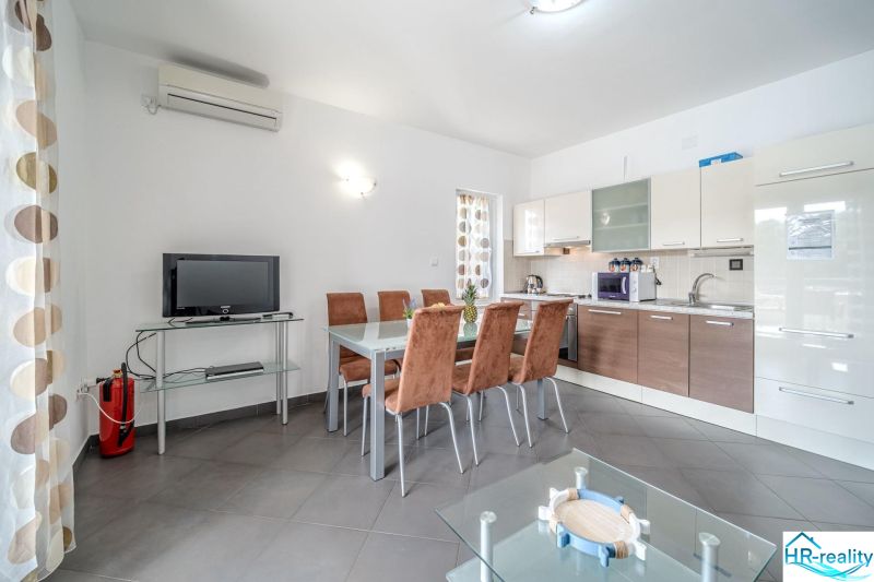 A bright kitchen with a dining table and a television in a holiday apartment.