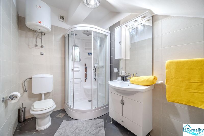 Bathroom in a holiday apartment with a modern shower and bright yellow towels.
