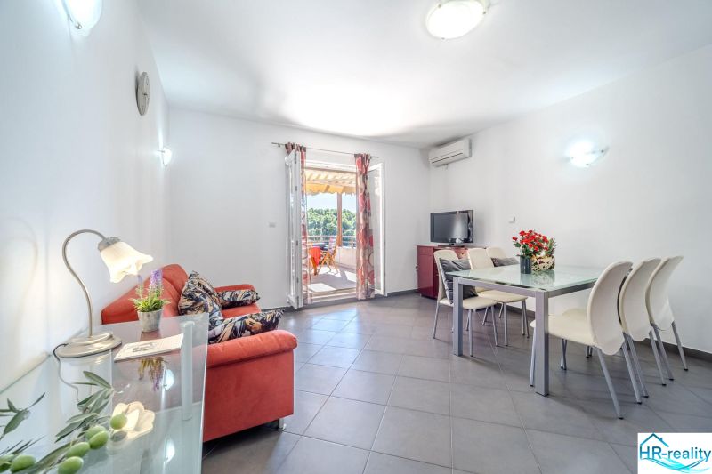 Bright living room with a sofa, dining table, and terrace in the Holiday Apartment.