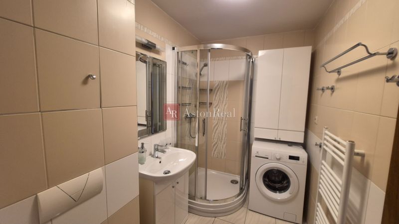 Bathroom with a sink, shower, and washing machine in a holiday apartment.