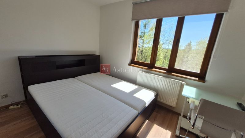 Bedroom with a double bed, wooden decor flooring, and a window in the Holiday Apartment.