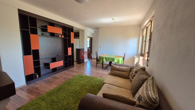 A recreational apartment with a wooden decor floor, a sofa, and a colorful wall unit.