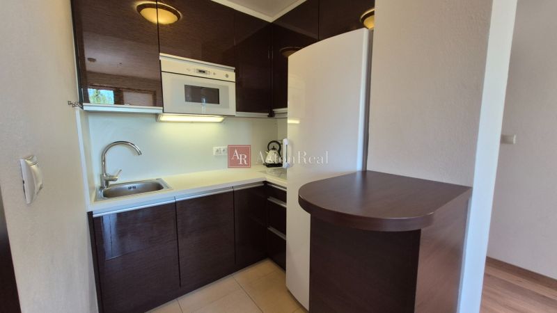 A kitchenette in a holiday apartment with dark cabinets and white appliances.