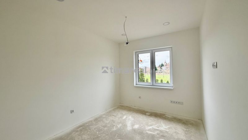 An empty room in a family house with white walls and a large window.