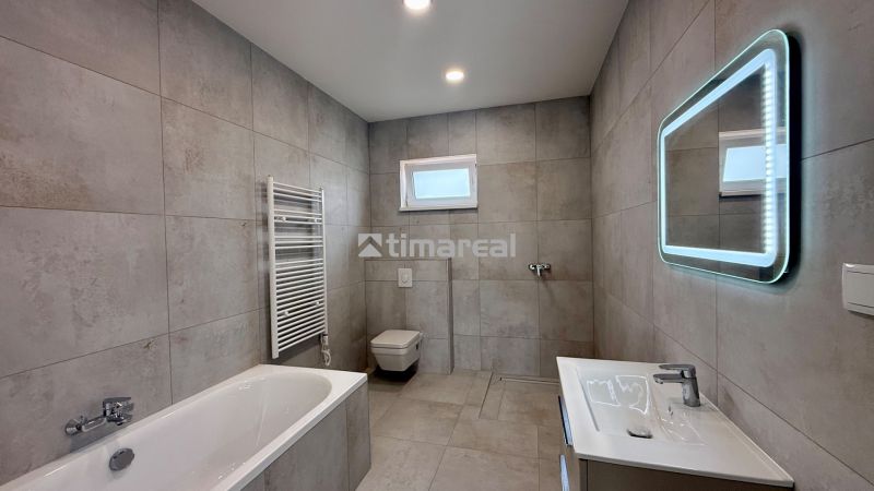 A family house bathroom with a bathtub, shower, and illuminated mirror.