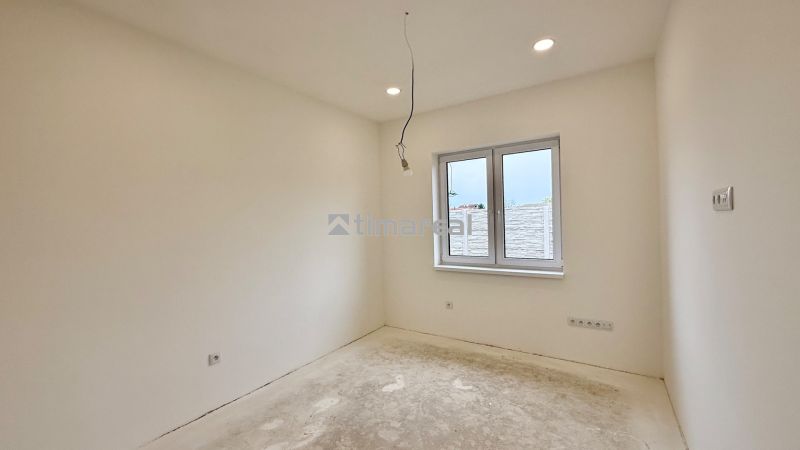 Bright room with a window and bare floor in a family house.