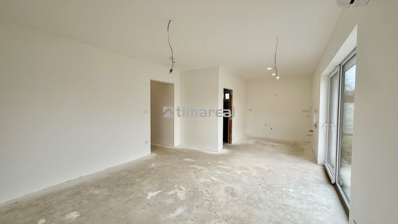A spacious room with plaster walls and large windows in a family house.