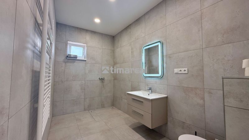 Bathroom in a family house with a modern sink, mirror, and ladder radiator.