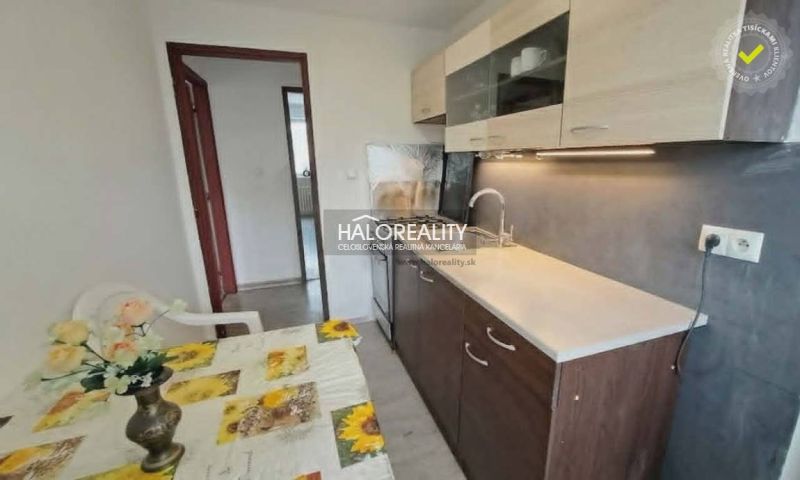 A kitchen in a 3-room apartment with a dining table, kitchen unit, and a wall in wooden decor.