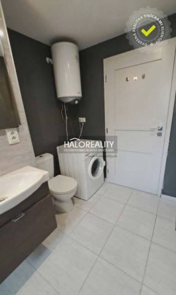 A bathroom in a 3-room apartment with a washing machine and a boiler, light-colored tiles.