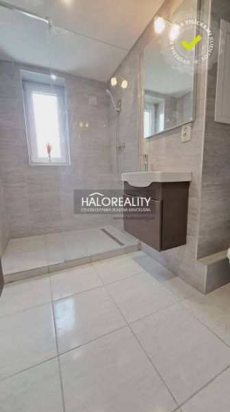 Bathroom in a 3-room apartment with a shower and a sink, light-colored tiles.
