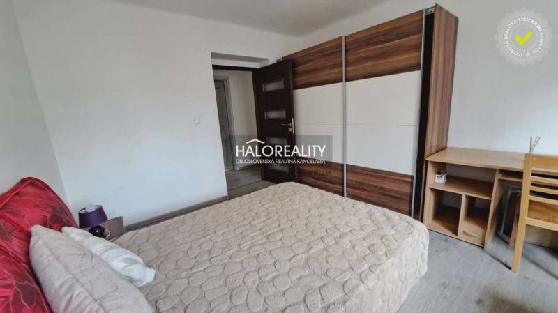 A bedroom with a wood-patterned floor, a built-in wardrobe, and a bed in a three-room apartment.
