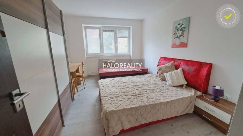 A bedroom with a red headboard and a wooden decor floor in a 3-room apartment.