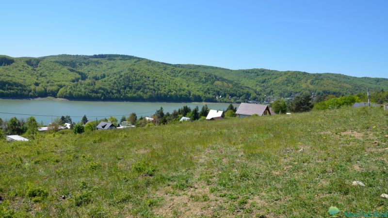Recreational plots in Nová Kelča with a view of green hills and a water surface.