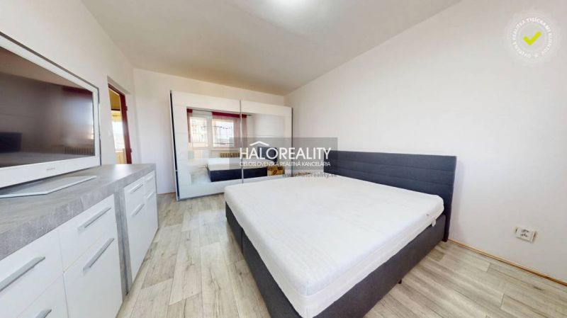 Bedroom in a two-room apartment with a wooden decor floor and a wardrobe.