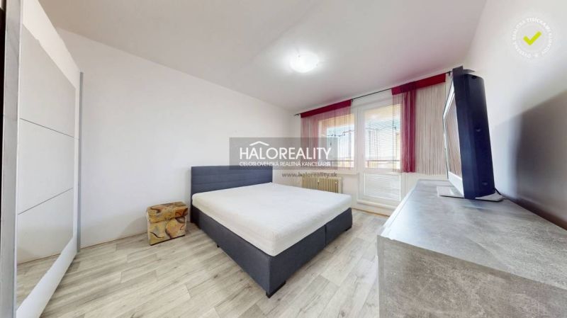 A bedroom with a bed, television, and a wooden decor floor in a two-room apartment.