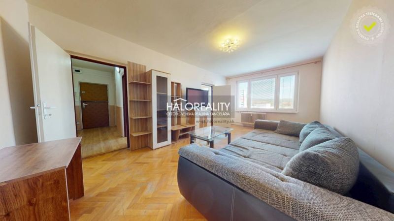 Living room with wood-patterned flooring, a sofa, and furniture in a two-room apartment.