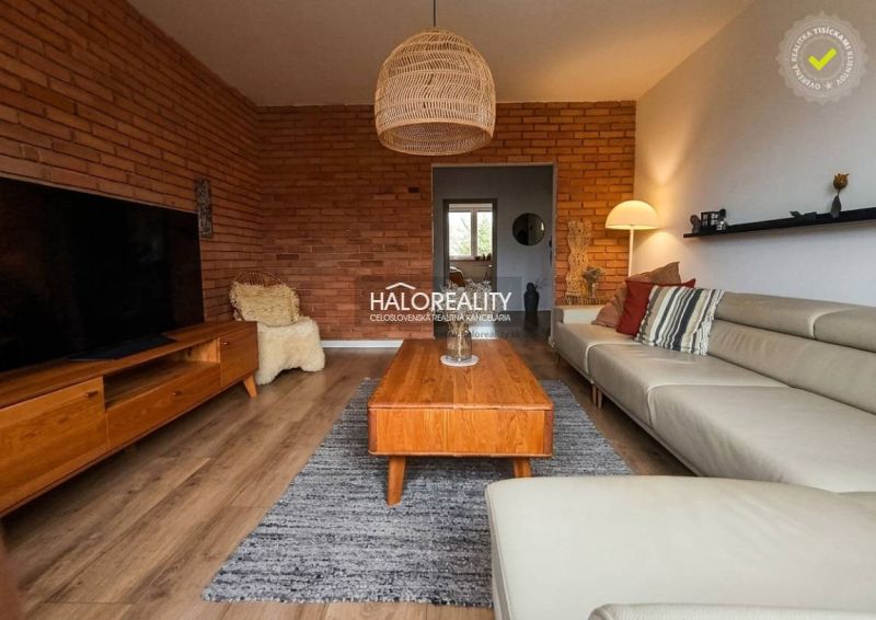 Living room in a 3-room apartment with a brick wall and a wooden decor floor.