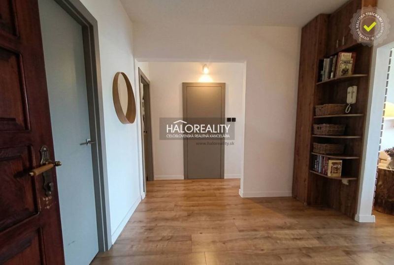 A hallway in a 3-room apartment with a wood-patterned floor and a built-in shelf.
