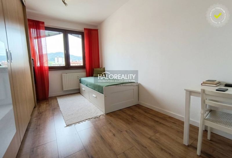 A bright room with a bed, a table, and a floor with a wooden decor in a 3-room apartment.