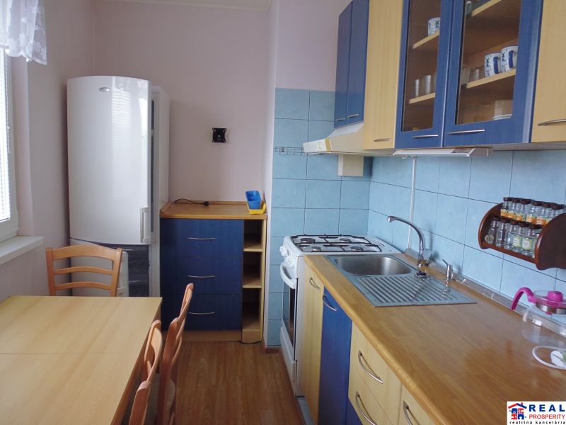 Kitchen area in a 2-room apartment with chairs, wooden decor flooring, blue tiles.
