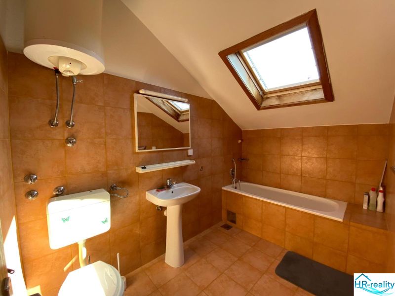 A bathroom in a holiday apartment with a bathtub and a skylight.