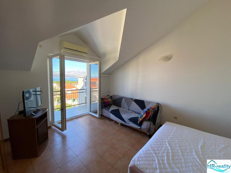 Room in a recreational apartment with a balcony and sea view, television, and sofa.
