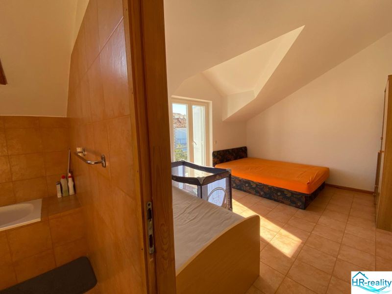Interior of a holiday apartment with a sofa, bed, and baby crib.