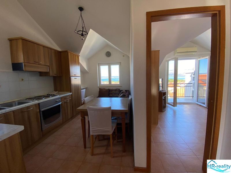 A kitchen of a holiday apartment with wooden cabinets and a sea view.